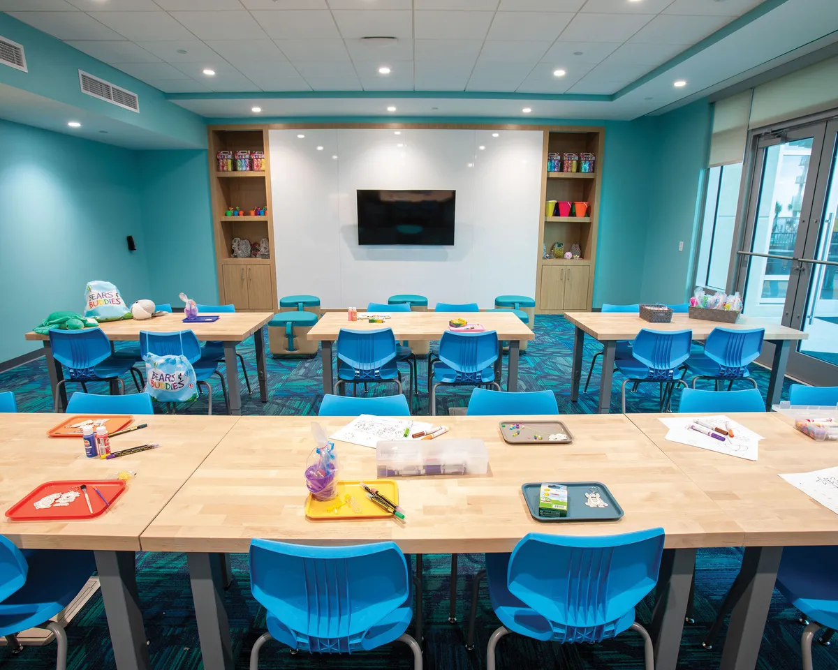 An inviting interior space set up for children’s art and craft sessions, featuring bright tables and chairs, art supplies, and colorful décor. The playful mood and creative materials suggest hands-on family engagement and learning opportunities.