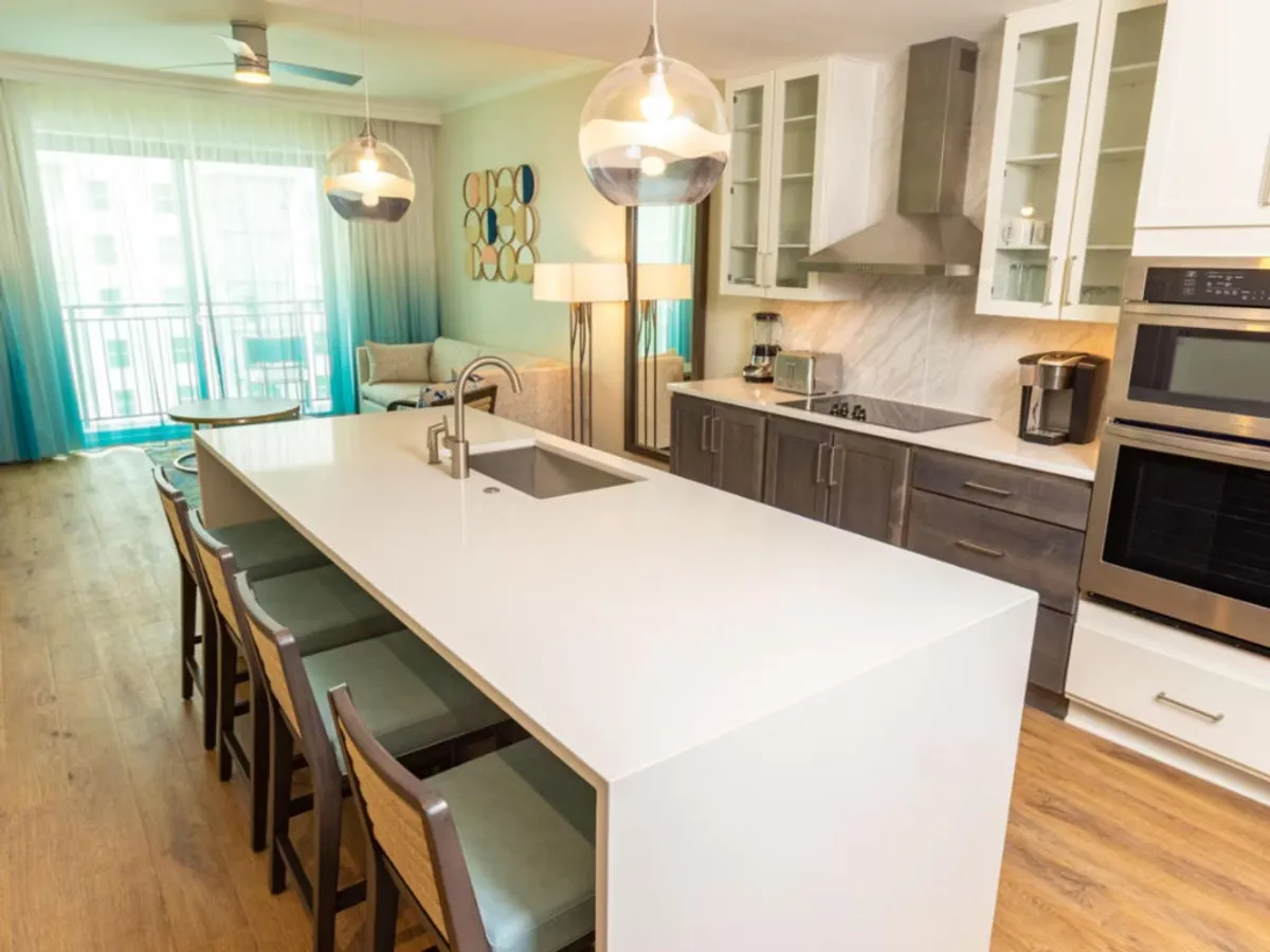 A spacious, contemporary open-concept interior featuring a kitchen island with modern appliances, a comfortable seating area, and large windows that bathe the space in natural light. The layout encourages interaction, with clear sightlines between the kitchen, dining, and living areas, evoking a sense of togetherness and ease.