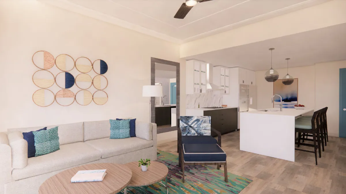 The image showcases a bright, stylish living space with a plush sofa adorned with colorful cushions, vibrant circle wall art, a modern island kitchen with sleek pendant lights, and a cheerful area rug. Sunlight pours in, highlighting spaces perfect for relaxed mornings, cozy evenings, and gatherings with loved ones.